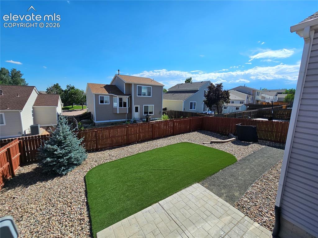 Image 24 of 26: Expansive backyard featuring artificial turf, a paved patio, and a gravel p
