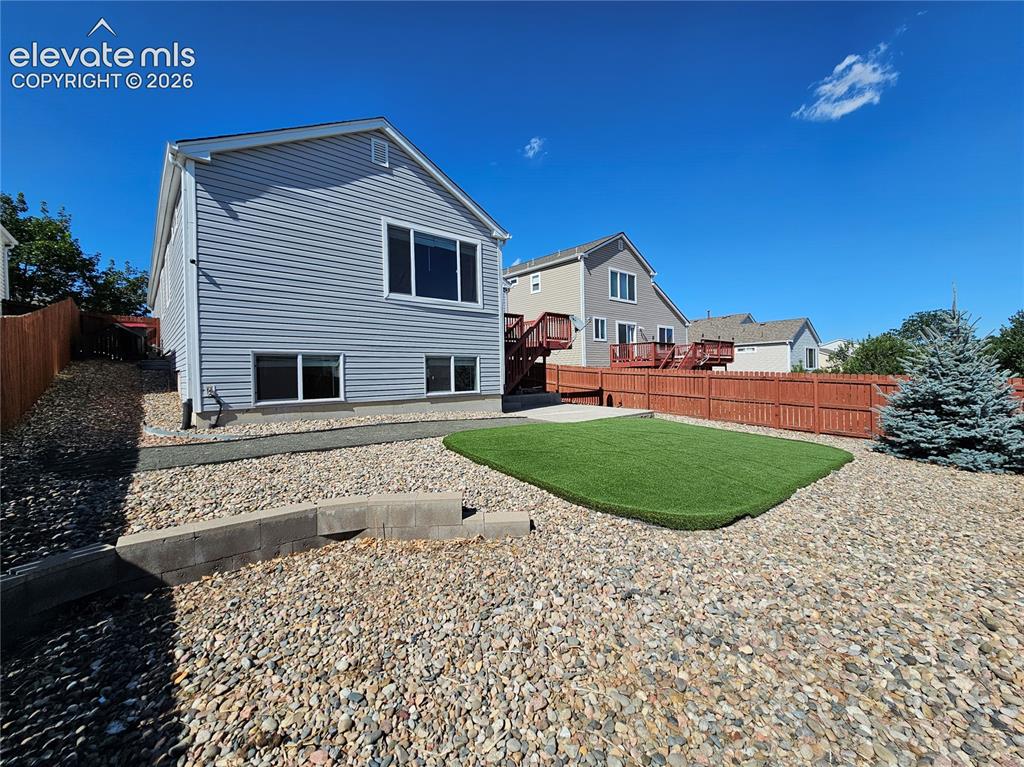 Image 25 of 26: Expansive backyard featuring a central artificial turf area, decorative gra