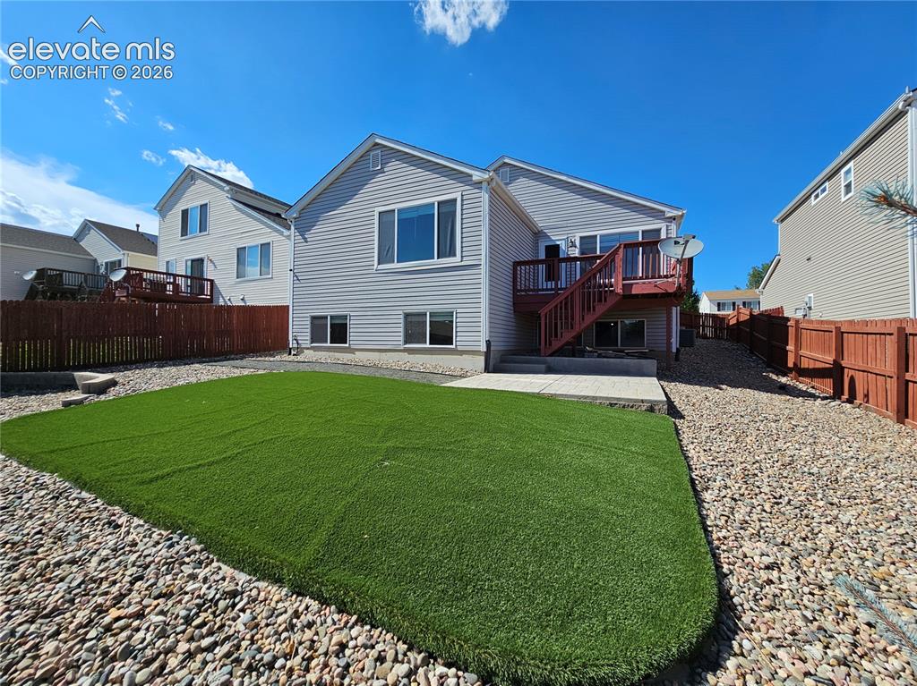 Image 26 of 26: Private backyard featuring a large artificial turf area, decorative stone l