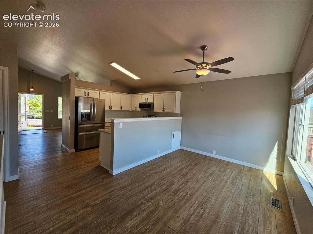 Image 8 of 26: Open-concept living space featuring wood-finish flooring, a contemporary ce