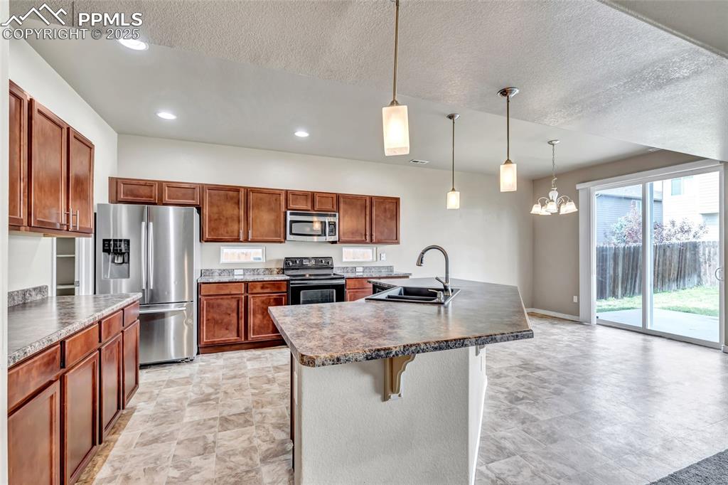 Image 11 of 50: Kitchen featuring stainless steel appliances, decorative light fixtures, a 