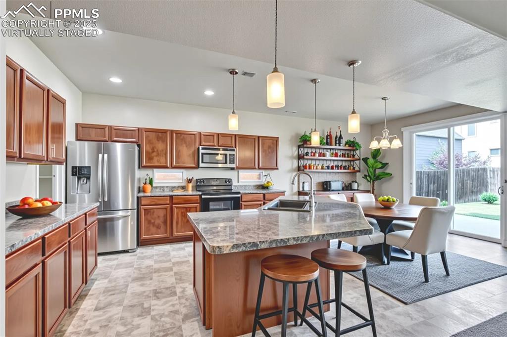 Image 12 of 50: Virtually Staged - Kitchen with stainless steel appliances, brown cabinetry