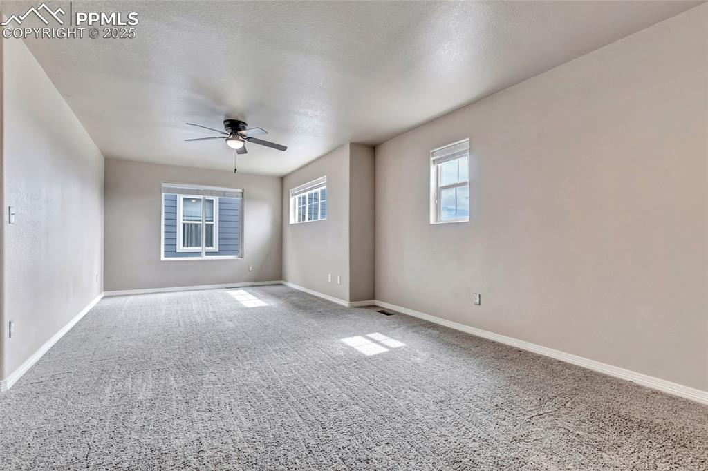 Image 18 of 50: Empty room with carpet floors, a ceiling fan, and a textured ceiling