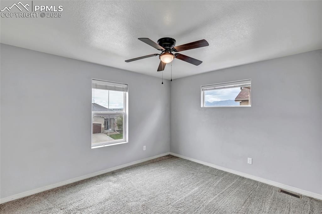 Image 31 of 50: Secondary bedroom with a textured ceiling and ceiling fan