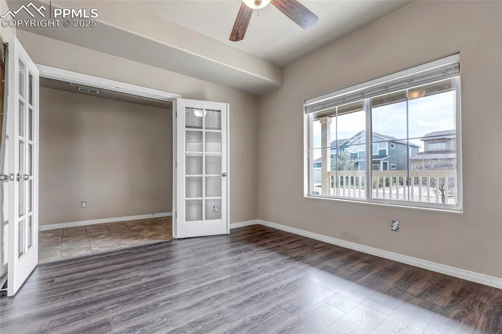 Image 5 of 50: Unfurnished room with french doors, wood finished floors, and a ceiling fan
