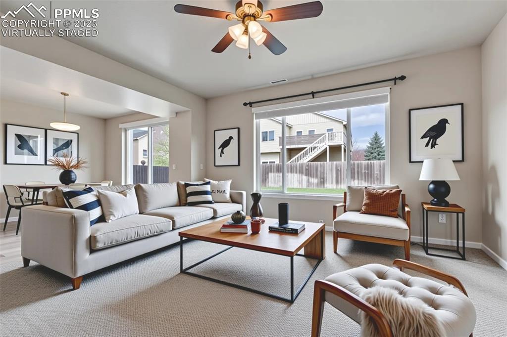 Image 8 of 50: Virtually Staged - Living area featuring ceiling fan and carpet flooring
