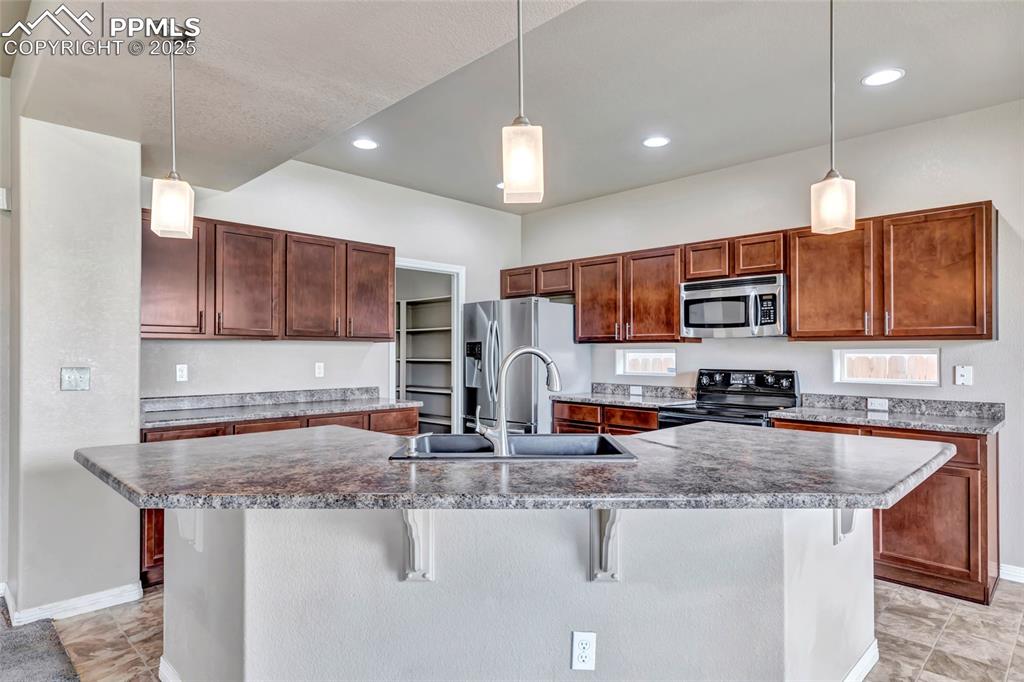 Image 9 of 50: Kitchen with decorative light fixtures, stainless steel appliances, a break
