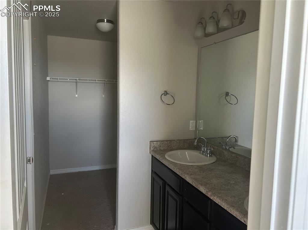 Image 6 of 8: Full bathroom with double vanity and a walk in closet