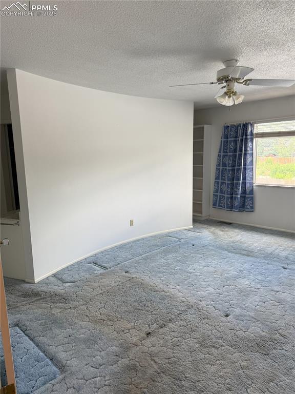 Image 11 of 33: Carpeted empty room featuring a textured ceiling and a ceiling fan