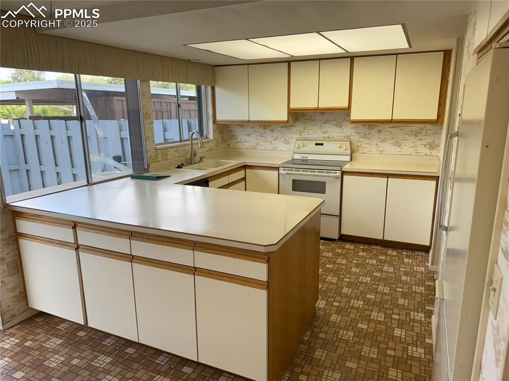 Image 3 of 33: Kitchen featuring wallpapered walls, white appliances, light countertops, a