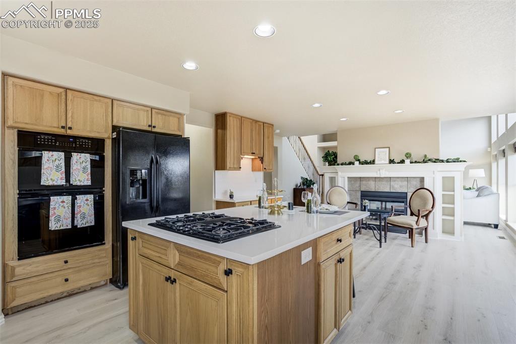 Image 15 of 50: Kitchen with black appliances, light wood-style flooring, light countertops