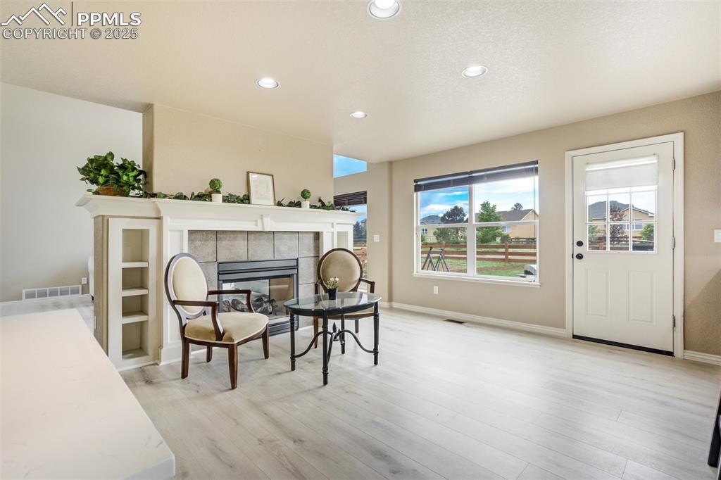 Image 16 of 50: Sitting room with light wood-style flooring, recessed lighting, and a firep