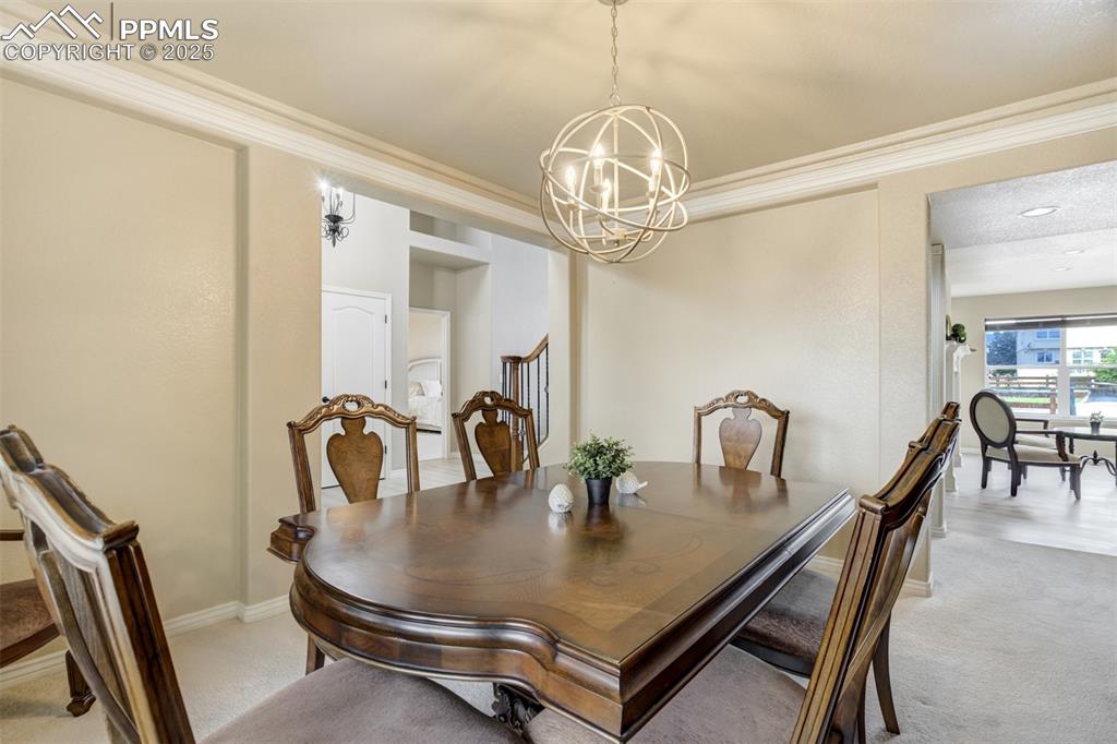 Image 18 of 50: Dining space with a chandelier, light carpet, and ornamental molding