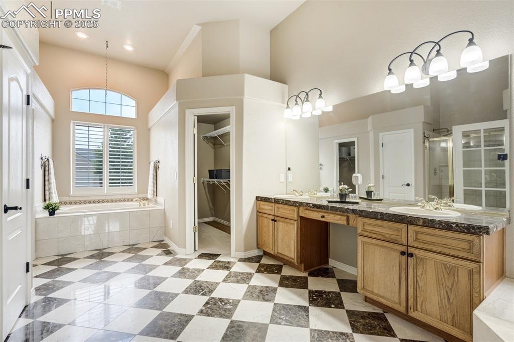 Image 23 of 50: Full bathroom featuring a walk in closet, double vanity, a bath, a shower s