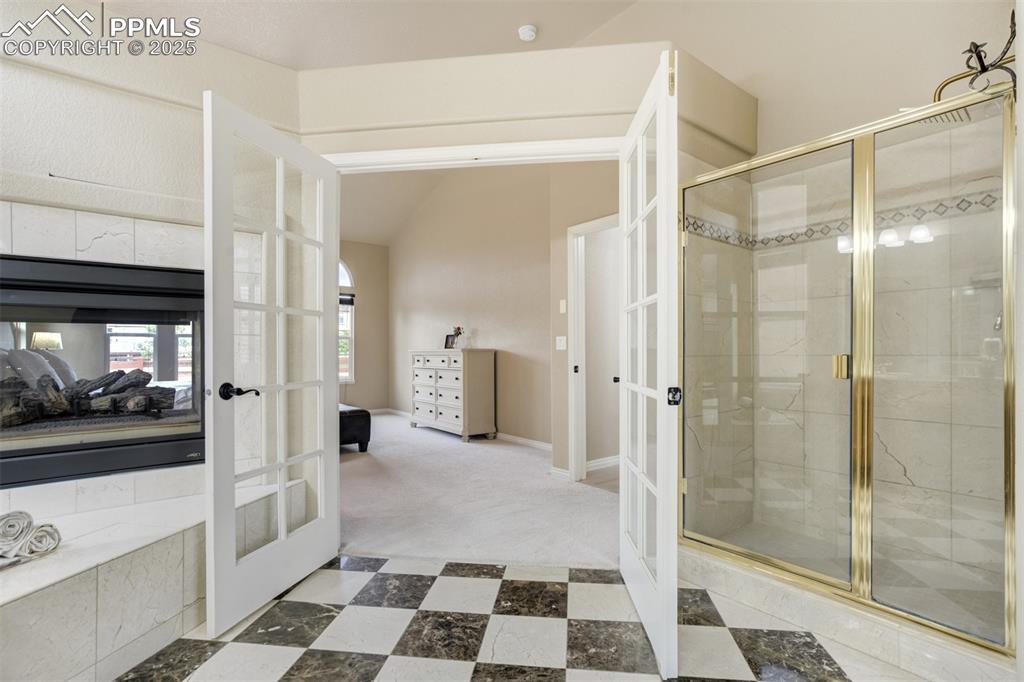 Image 25 of 50: Full bathroom featuring french doors, a stall shower, lofted ceiling, and c