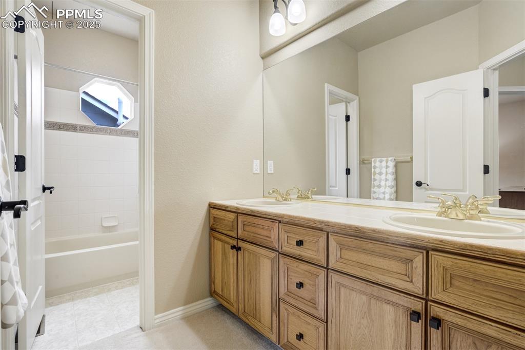 Image 35 of 50: Full bathroom featuring double vanity and washtub / shower combination