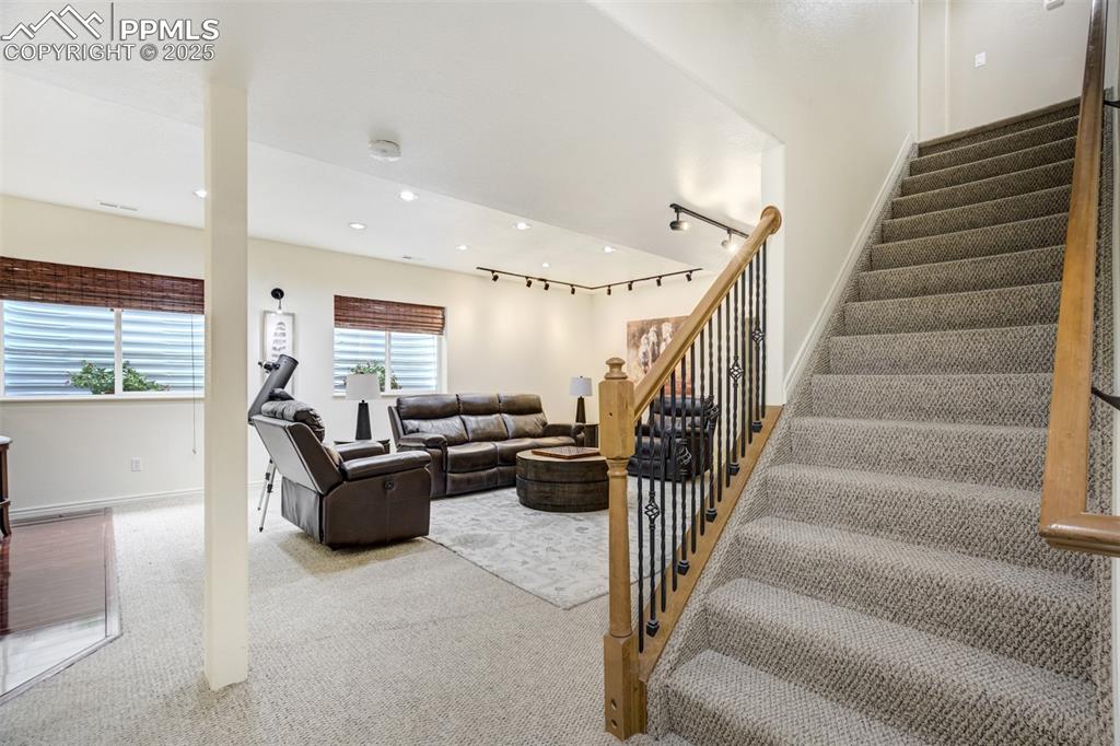 Image 36 of 50: Living area with stairs, carpet floors, and recessed lighting