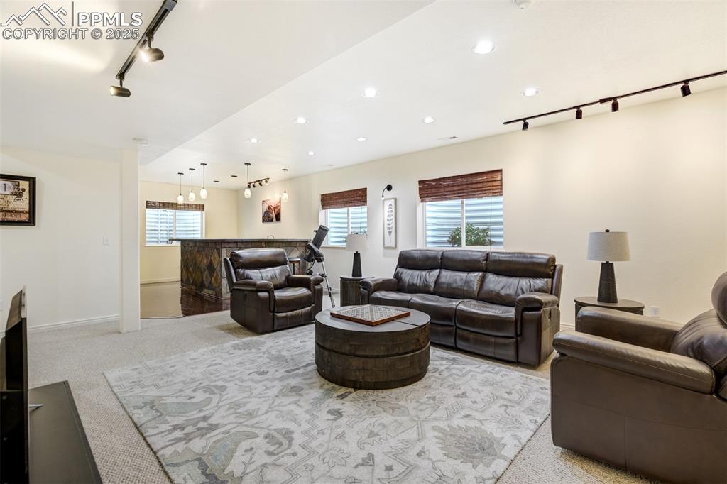 Image 37 of 50: Carpeted living area featuring track lighting, a dry bar, and recessed ligh