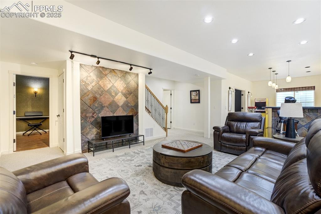 Image 39 of 50: Living room featuring rail lighting, light carpet, recessed lighting, stair