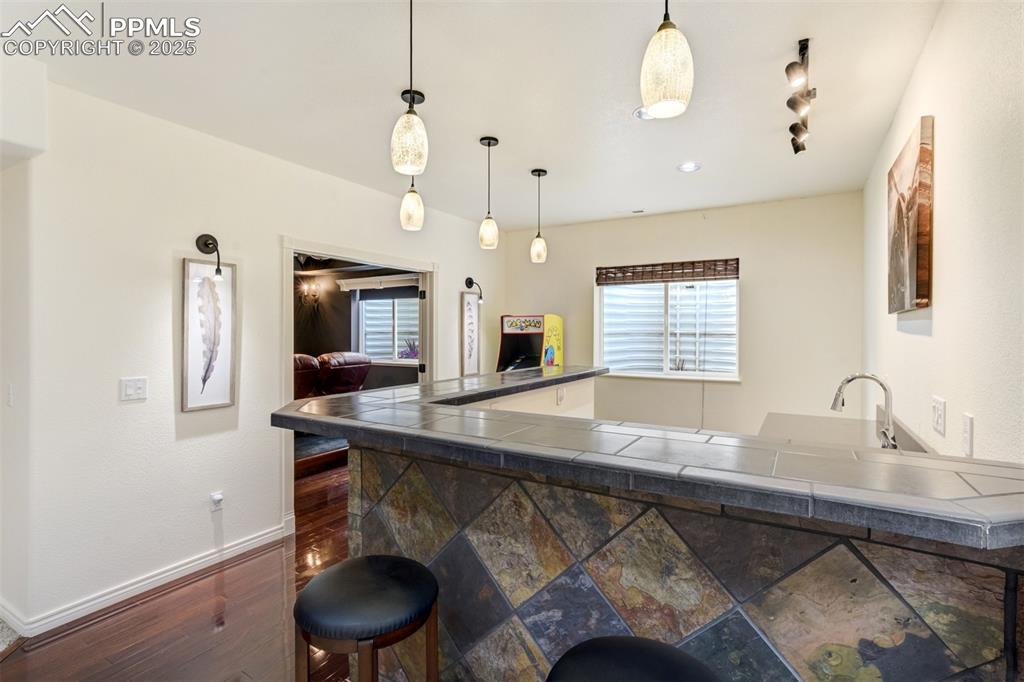 Image 40 of 50: Kitchen featuring decorative light fixtures, a breakfast bar, and tile coun