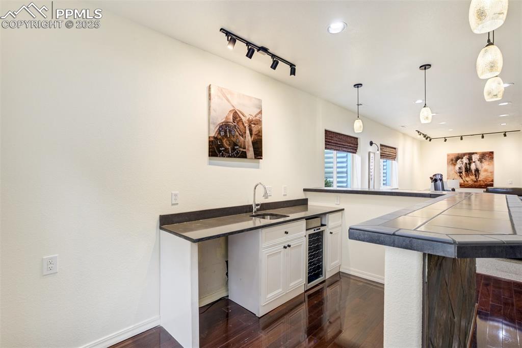 Image 41 of 50: Kitchen featuring rail lighting, dark wood finished floors, white cabinets,