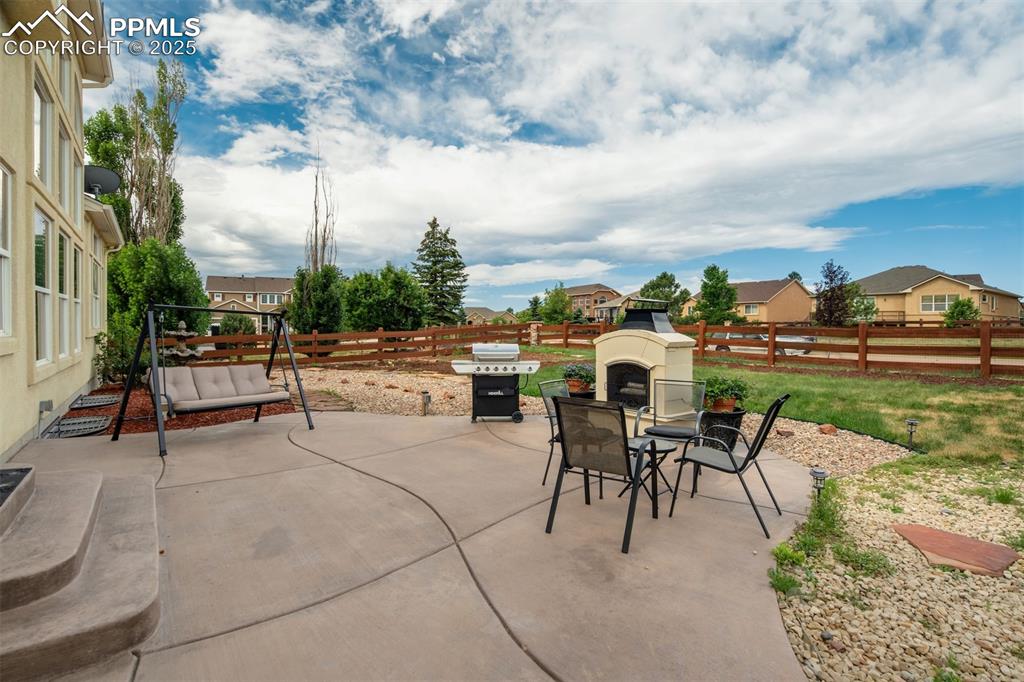 Image 46 of 50: Fenced backyard featuring a patio, an outdoor fireplace, area for grilling,