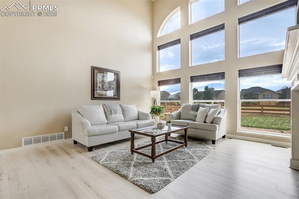 Image 7 of 50: Living area featuring wood finished floors and a towering ceiling