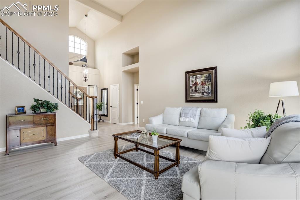 Image 9 of 50: Living area featuring high vaulted ceiling, stairway, wood finished floors,