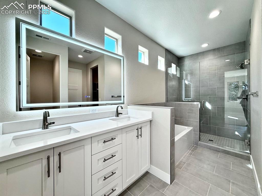 Image 22 of 33: Full bath featuring double vanity, a stall shower, a garden tub, recessed l