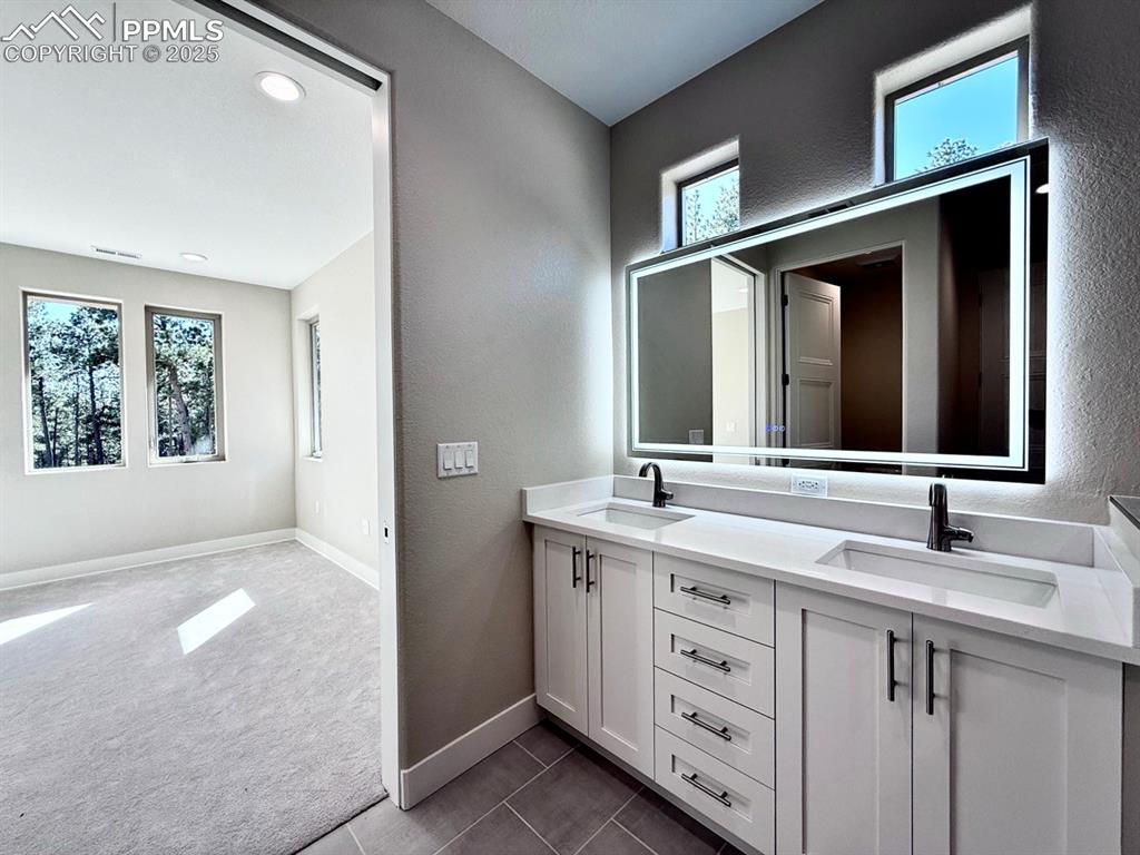 Image 23 of 33: Full bathroom with double vanity, dark colored carpet, a textured wall, and