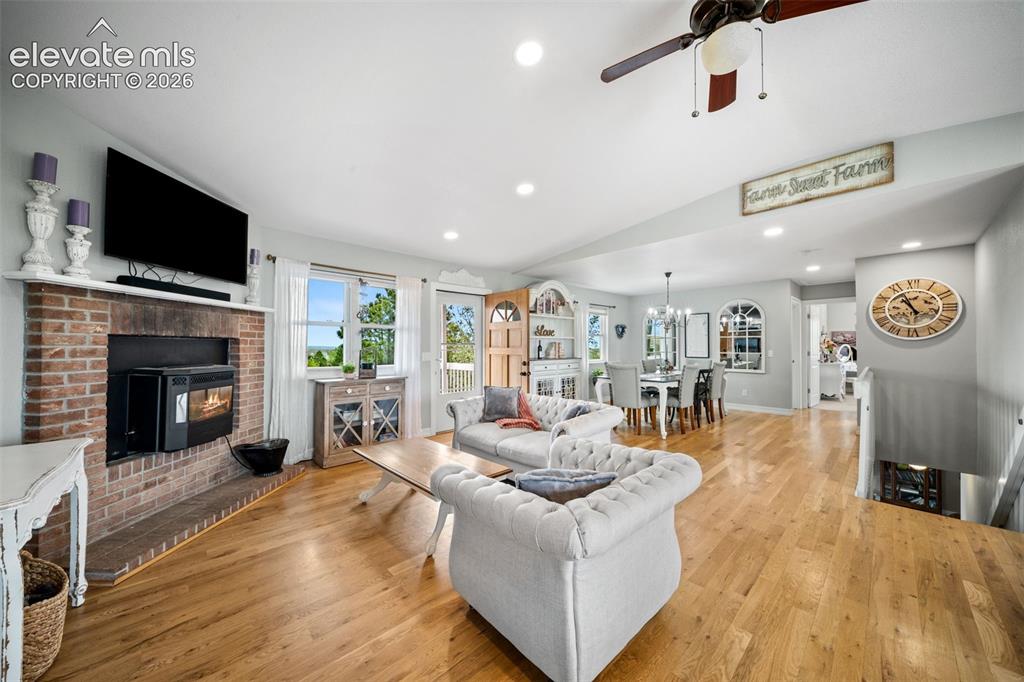 Image 10 of 50: Open-concept living area featuring wood-finish flooring, a brick-surround f