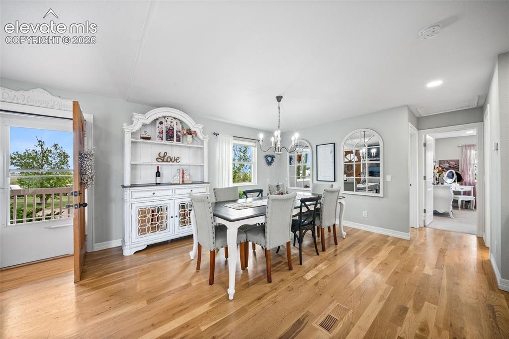 Image 17 of 50: Dining area featuring wood-finish flooring, a contemporary chandelier, ligh
