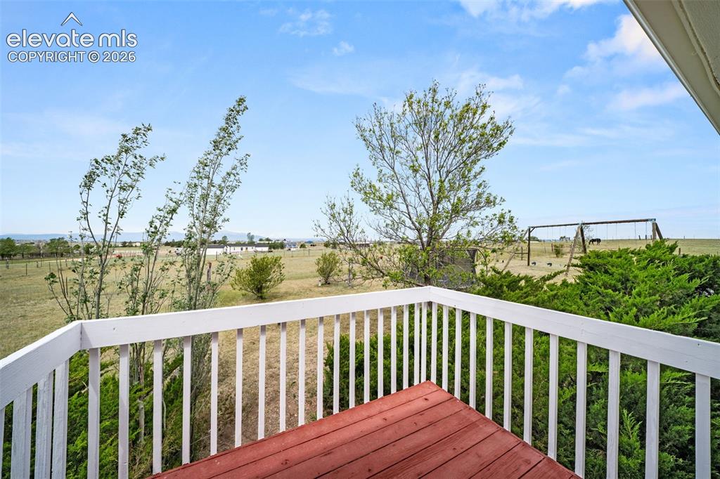 Image 21 of 50: Exterior wood deck featuring a red-stained surface and white painted railin