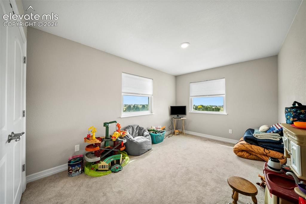 Image 23 of 50: Carpeted interior space featuring two windows with roller shades, recessed
