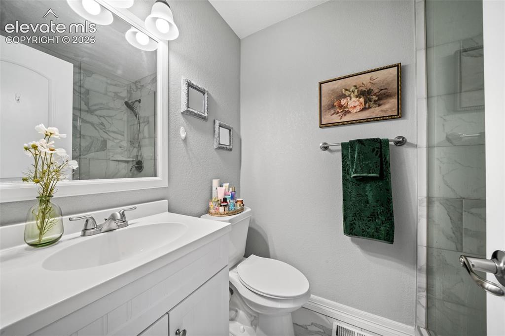 Image 24 of 50: Bathroom featuring a white vanity with integrated sink, chrome faucet, wall