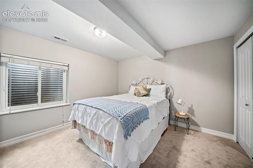 Image 29 of 50: Bedroom featuring neutral wall paint, light-colored carpeting, and a white