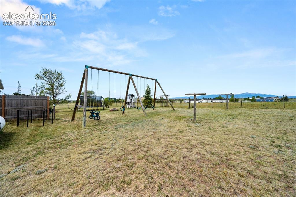 Image 34 of 50: Expansive outdoor area featuring a swing set, additional play equipment, an