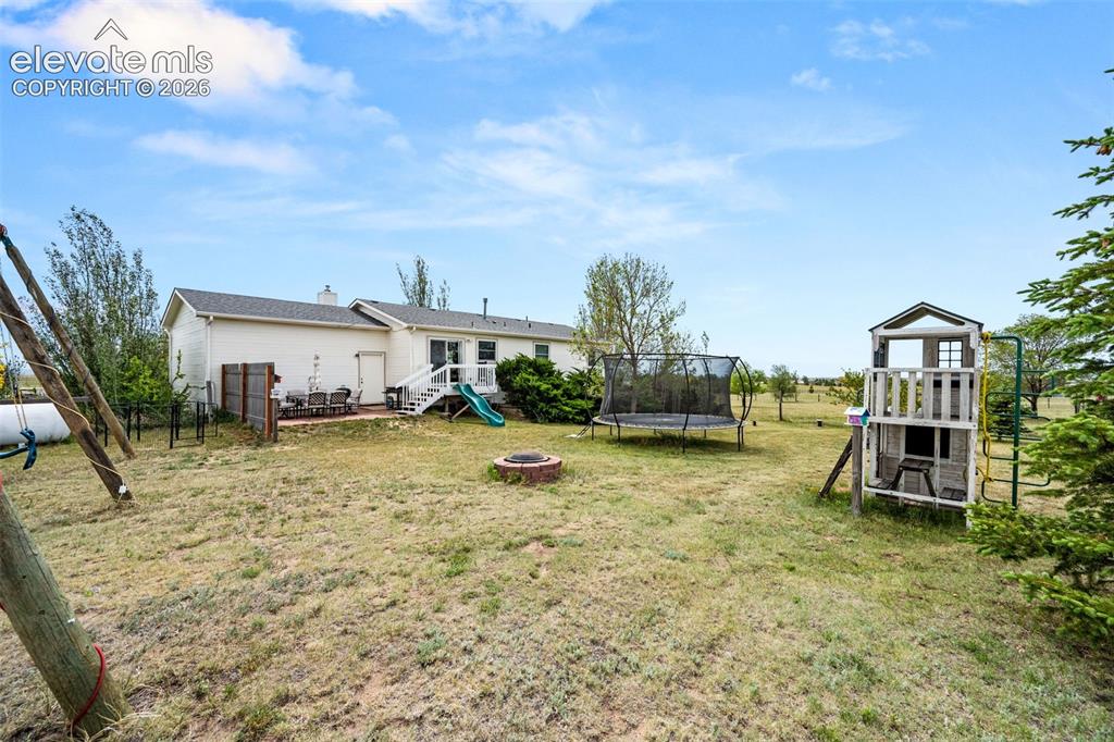 Image 35 of 50: Expansive rear yard featuring a paved patio, multi-level deck with white ra