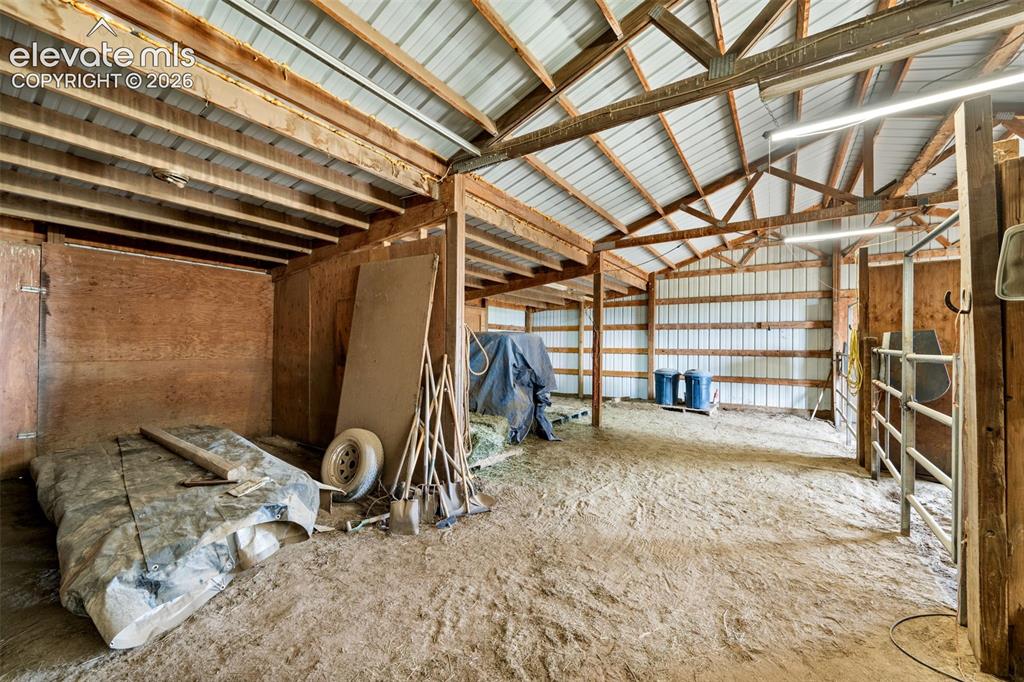 Image 41 of 50: Spacious barn interior featuring exposed wood beams, a corrugated metal roo