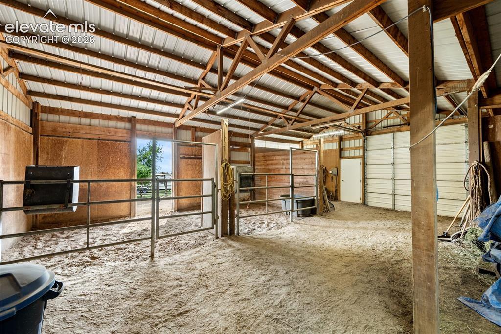 Image 43 of 50: Indoor arena featuring a sand base, exposed wood beams, and a metal roof