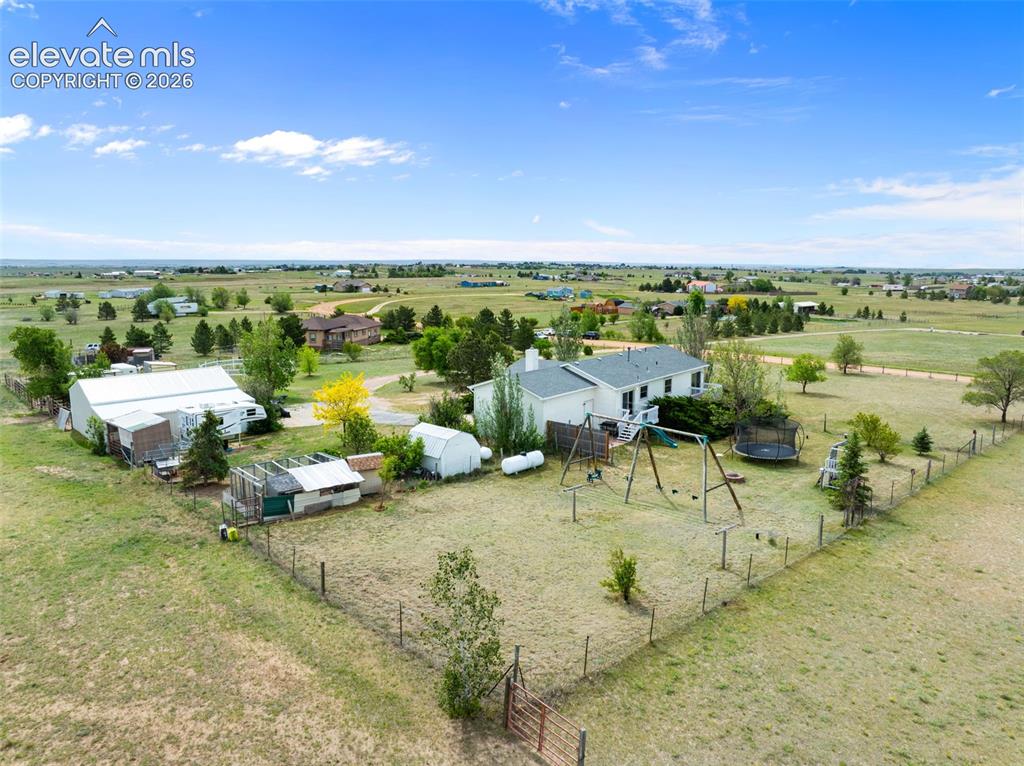 Image 48 of 50: Expansive rural property featuring a white residence with a dark roof, mult