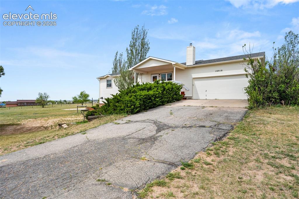Image 6 of 50: Ranch-style exterior with an attached two-car garage, covered entry, and a