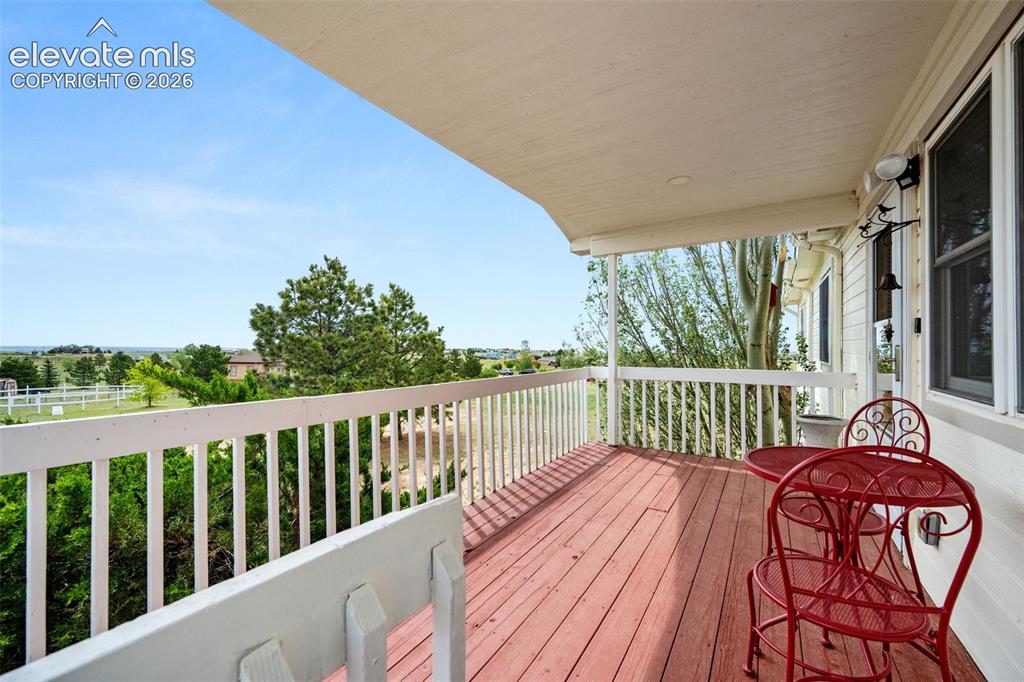 Image 7 of 50: Covered wood-deck balcony with white railing