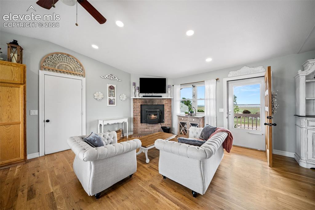 Image 9 of 50: Living area featuring wood-finish flooring, a brick fireplace, recessed lig
