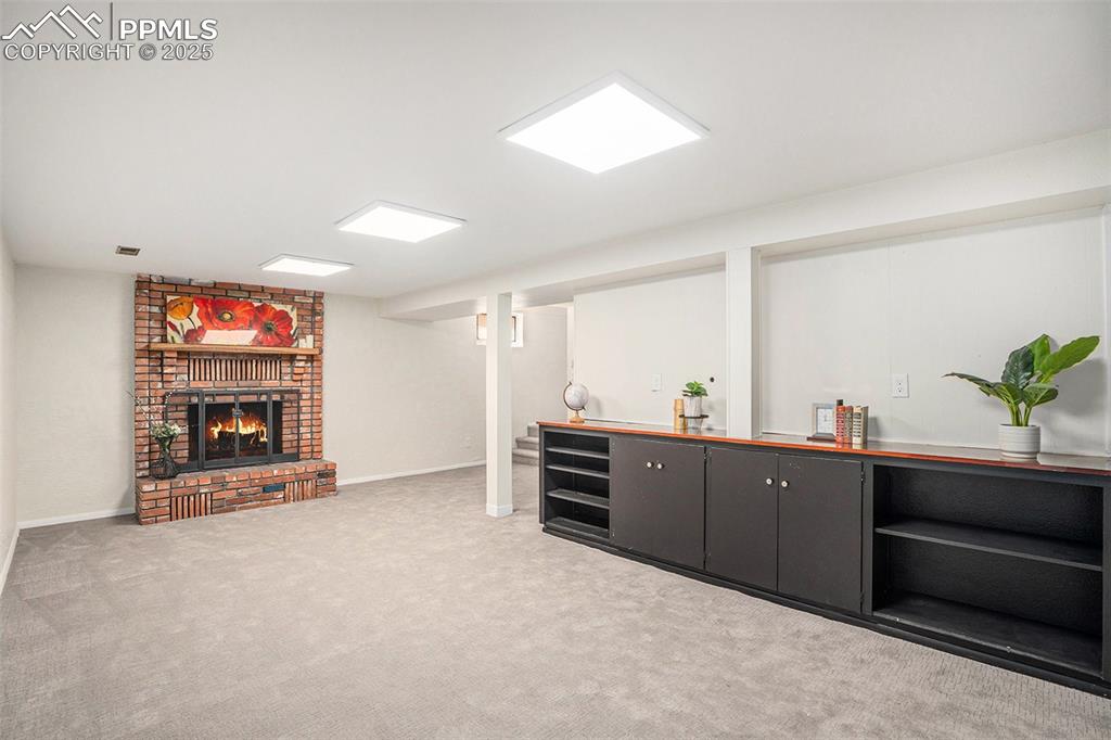 Image 13 of 24: Bar with a brick fireplace, light colored carpet, light countertops, and da