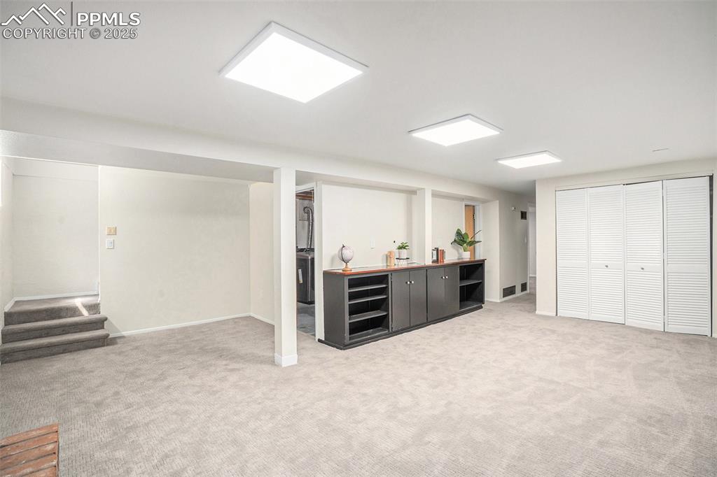 Image 14 of 24: Finished basement with light colored carpet and baseboards