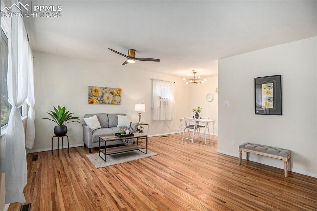 Image 4 of 24: Living area featuring light wood-type flooring, a ceiling fan, and a chande