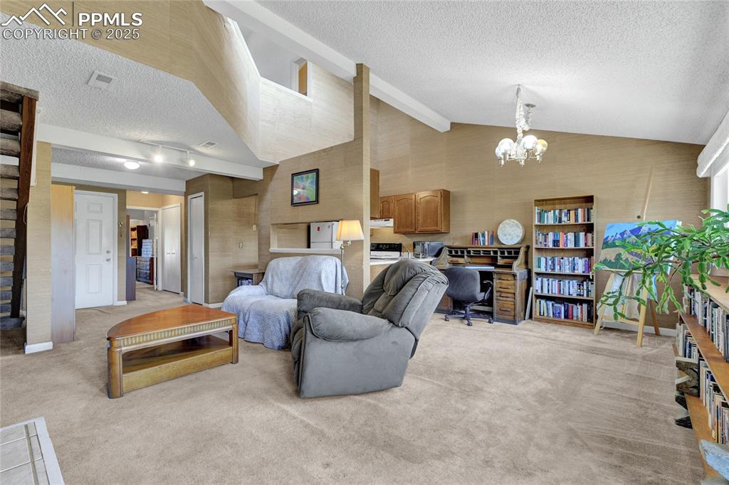 Image 10 of 22: Living room featuring a textured ceiling, light carpet, a chandelier, and v