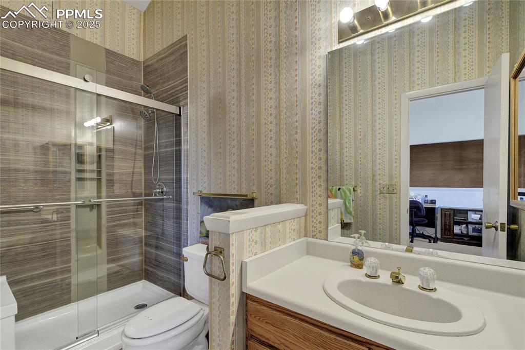 Image 19 of 22: Bathroom featuring wallpapered walls, vanity, and a shower stall
