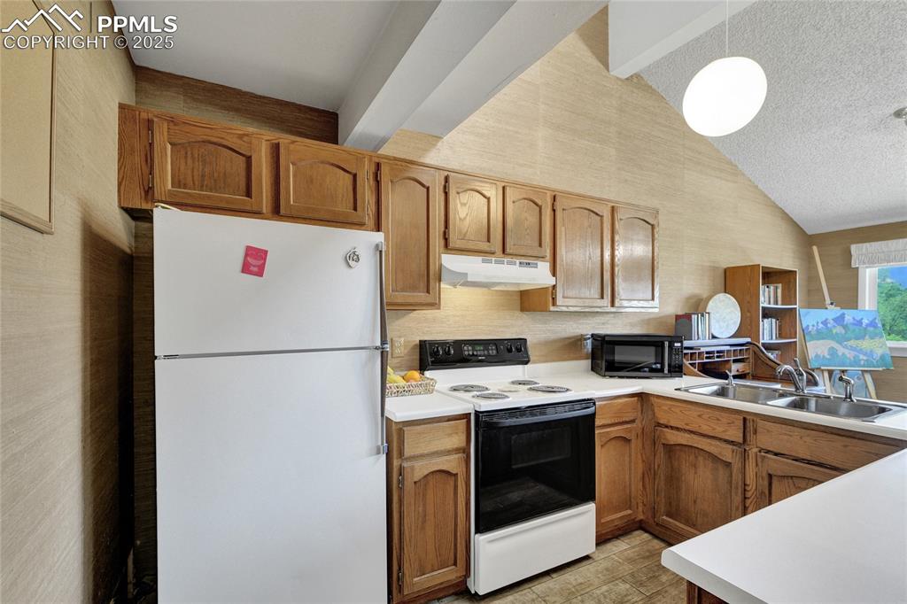 Image 8 of 22: Kitchen with freestanding refrigerator, electric range, black microwave, un